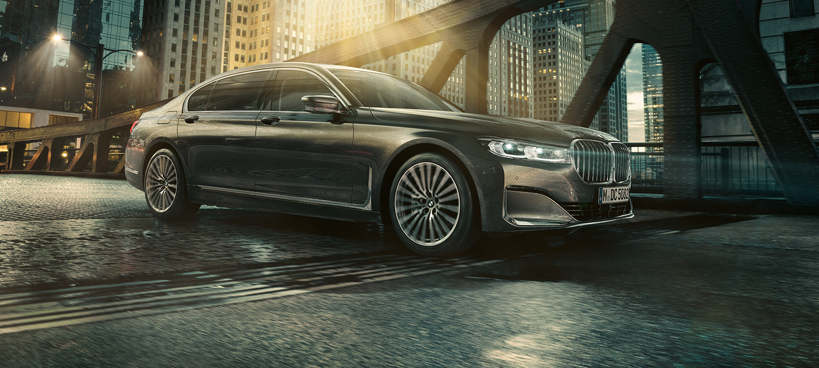 BMW Série 7 Berlina, perspetiva lateral Perspetiva lateral do BMW Série 7 Berlina com porta aberta em frente a um hotel iluminado