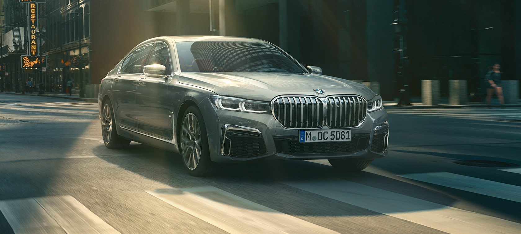 BMW Série 7 Berlina em cinza, perspetiva frontal a três quartos Perspetiva frontal a três quartos do BMW Série 7 Berlina em cinza em movimento num cenário urbano