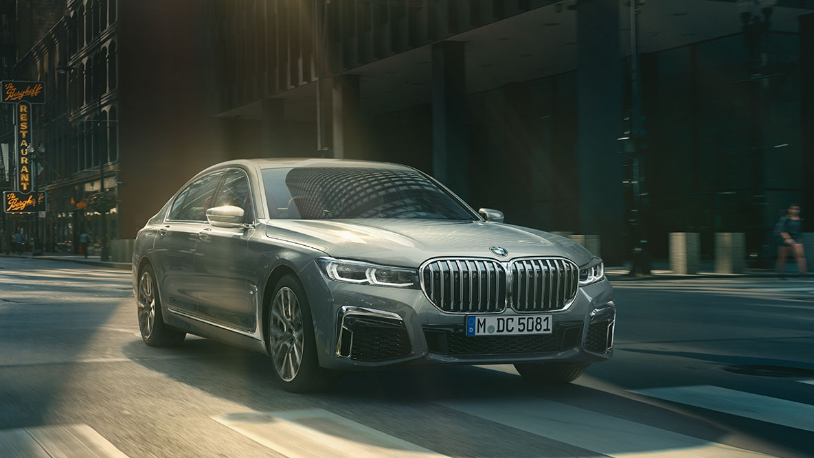 Assistente de condução Professional: perspetiva frontal a três quartos do BMW Série 7 Berlina em movimento em frente a um cenário urbano Assistente de condução Professional do BMW Série 7 Berlina